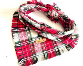 May include: A red, white, and green tartan dog bandana with fringed edges. The bandana is knotted and features a small tag with the text "Fur's Cafe". The tartan pattern is a traditional design.