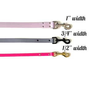 May include: Three dog leashes in different colors and widths. The top leash is light pink and 1 inch wide. The middle leash is gray and 3/4 inch wide. The bottom leash is pink and 1/2 inch wide.