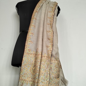 May include: A beige shawl with brown and gold embroidery. The shawl has a striped pattern and a paisley design.