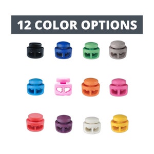 Könnte beinhalten: Zwölf Farboptionen für Kunststoff-Schieberverschlüsse. Die Verschlüsse sind klein und haben zwei Löcher. Die Farben sind Schwarz, Blau, Grün, Grau, Hellblau, Rosa, Orange, Magenta, Rot, Lila, Weiß und Gelb.