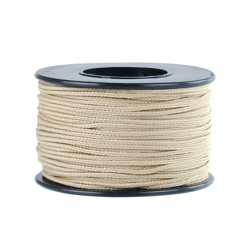 Puede incluir: Una bobina de cord&oacute;n beige enrollada alrededor de una bobina de pl&aacute;stico negro.