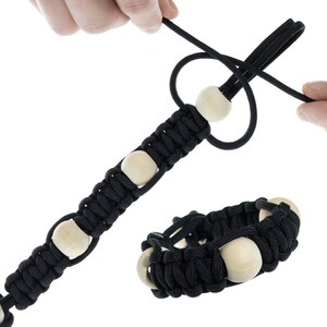 May include: A black paracord bracelet with wooden beads. The bracelet is shown being tied around a wrist.