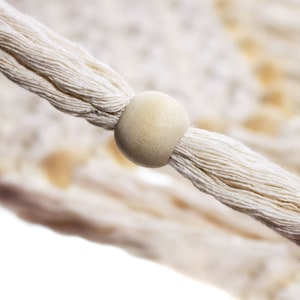 May include: Close-up of a white cotton rope with a natural wood bead. The rope is woven together and the bead is smooth and round.