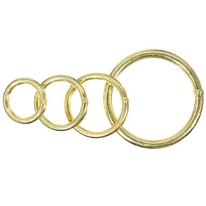 May include: Four gold-colored metal rings of different sizes, arranged in a row from smallest to largest.