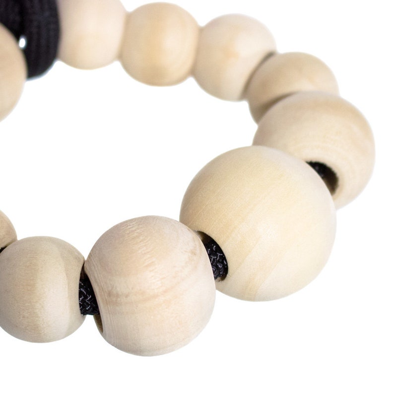 May include: A close-up of a wooden bead necklace with natural colored beads and a black cord.