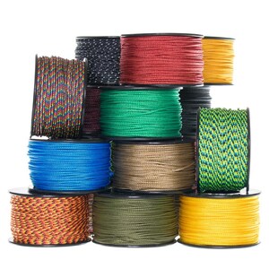 Puede incluir: Una colecci&oacute;n de carretes de cord&oacute;n de colores, incluyendo rojo, verde, azul, amarillo y negro. Los carretes est&aacute;n apilados uno encima del otro, con los extremos del cord&oacute;n visibles.
