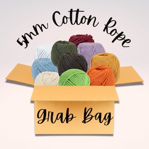 May include: A cardboard box with the text "Grab Bag" printed on the front. The box is filled with 10 balls of 5mm cotton rope in various colors, including white, blue, green, brown, red, purple, orange, and yellow.