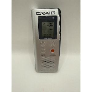 May include: A silver Craig IC recorder with a digital display showing 00, a speaker grille at the bottom, and control buttons labelled REV, FWD, MODE/PAUSE, and ERASE/REPEAT. The device features a black side panel and a rectangular screen.