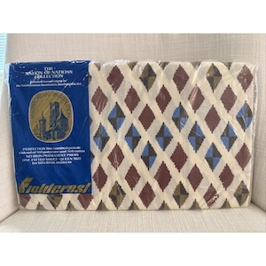 May include: A Queen size fitted sheet from the Nation of Nations Collection. The sheet features a diamond pattern in shades of brown, blue, and tan. The packaging includes text from the Smithsonian Institution and Fieldcrest.
