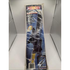 May include: A Flying Model Rocket kit for the SR-71 Blackbird, in a clear plastic sleeve. The kit features a black rocket model with fins and a nose cone, and includes the text "Flying Model Rocket" and "Blackbird".