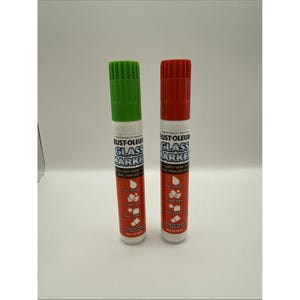 May include: Two glass paint markers, one green and one red, are displayed against a white background. The markers are cylindrical with white bodies and black text. The green marker has a green cap, and the red marker has a red cap. The text on the markers reads "RUST-OLEUM GLASS MARKER".