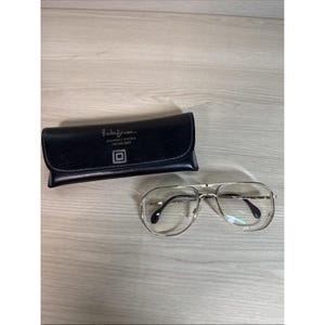 May include: A pair of silver-framed aviator eyeglasses with clear lenses and a black leather glasses case. The case has the text "Bradley Opticians" and a logo.