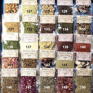 May include: A selection of dried herbs and botanicals, each packaged in a small, clear plastic bag. The bags are labelled with the herb's name, including "Orange Peel" and "Rosemary," and other text. The herbs display a variety of colours and textures, from orange peel to green leaves and red petals.
