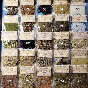 May include: A display of dried herbs and spices in small, labelled bags within a wooden drawer. The bags are numbered and contain items like comfrey root, cloves, and fennel seed. Measurements are in grams.