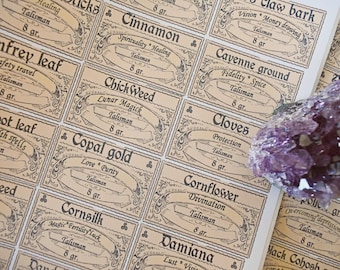 May include: A collection of small, rectangular labels with vintage-style typography. Each label features a different herb or flower name, along with a description of its magical properties and the word "Talisman". The labels are printed on a light brown background with black ink. A large amethyst crystal is resting on top of the labels.
