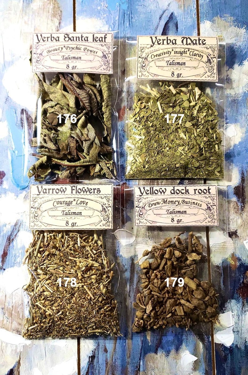 May include: Four small, clear plastic bags filled with dried herbs. Each bag has a label with text such as "Verba Santa leaf" and "Yerba Mate". The labels also include the word "Talisman" and the weight, 8 g. The background is a blue and white painted surface.