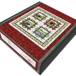 以下が含まれることがあります： 黒の縁取りのある赤、緑、白のキルト。キルトには、屋根付き橋の画像が描かれた正方形が4つあります。キルトは折り畳まれて、黒い箱の上に置かれています。