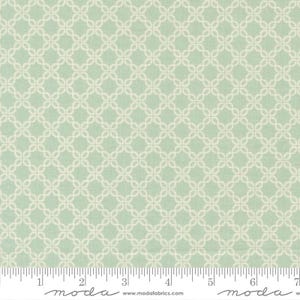 May include: A fabric with a repeating cream-colored geometric pattern on a light green background. The pattern consists of interlocking circles arranged in a grid. The fabric is marked with a ruler along the bottom edge.