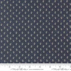 May include: Dark blue fabric featuring a repeating pattern of small, beige floral clusters and tiny white dots. A ruler at the bottom is marked in inches. Suitable for quilting or sewing projects.
