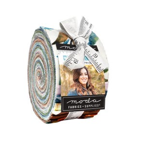 May include: A rolled bundle of fabric strips with a floral pattern in shades of blue, green, and brown. The bundle is tied with a white ribbon printed with measurements. A tag with the "moda FABRICS + SUPPLIES" logo is attached.