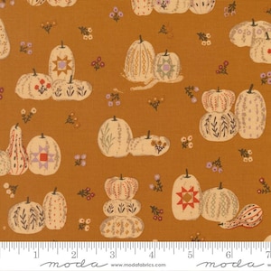 Könnte beinhalten: Ein senfgelber Stoff mit einem sich wiederholenden Muster aus cremefarbenen Kürbissen und Kalebassen. Die Kürbisse sind mit verschiedenen geometrischen Formen, Sternmotiven und floralen Linien verziert. Kleine Gruppen winziger violetter und brauner Blumen sind zwischen den Kürbissen verstreut. Ein weißes Lineal ist am unteren Rand sichtbar.