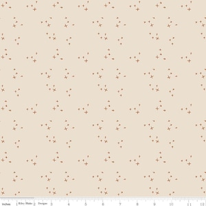 May include: A beige fabric with a repeating pattern of small brown stars and plus signs.