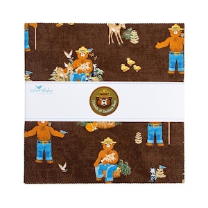 Puede incluir: Un montón de cuadrados de tela con un patrón repetido de Smokey Bear y animales del bosque sobre un fondo marrón. La tela tiene una banda blanca con el logotipo de Riley Blake Designs y un emblema de Smokey Bear.