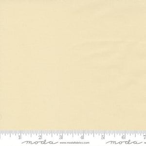 Könnte beinhalten: Ein einfarbiger, hellgelber Stoff mit einer dezenten Textur. Am unteren Rand befindet sich ein Lineal mit Zentimetermessungen. Der Markenname "moda" und die Website-Adresse sind unten aufgedruckt.