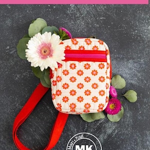 May include: A small white crossbody bag with a red strap and a floral print. The bag has a pink zipper and a red and pink stripe across the top. The bag is on a dark gray background with flowers.
