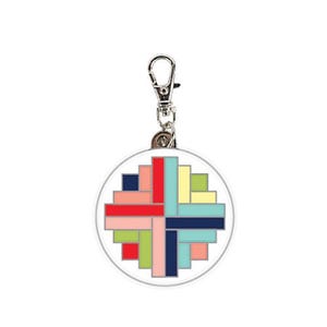 May include: A round keychain with a colorful geometric design. The design features a variety of colors, including red, blue, green, yellow, and pink. The keychain is attached to a silver metal ring.