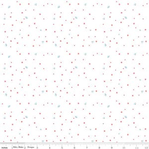 May include: White fabric with a repeating pattern of small red stars, tiny red dots, and light blue floral-like shapes. The pattern is evenly distributed across the surface. The bottom of the image shows a ruler in inches.