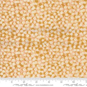 May include: A pink and gold fabric with a small white floral pattern. The fabric is shown with a ruler for scale.