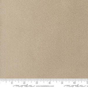 May include: A close-up of a beige, textured fabric. The fabric has a soft, fuzzy feel and is ideal for crafting projects.