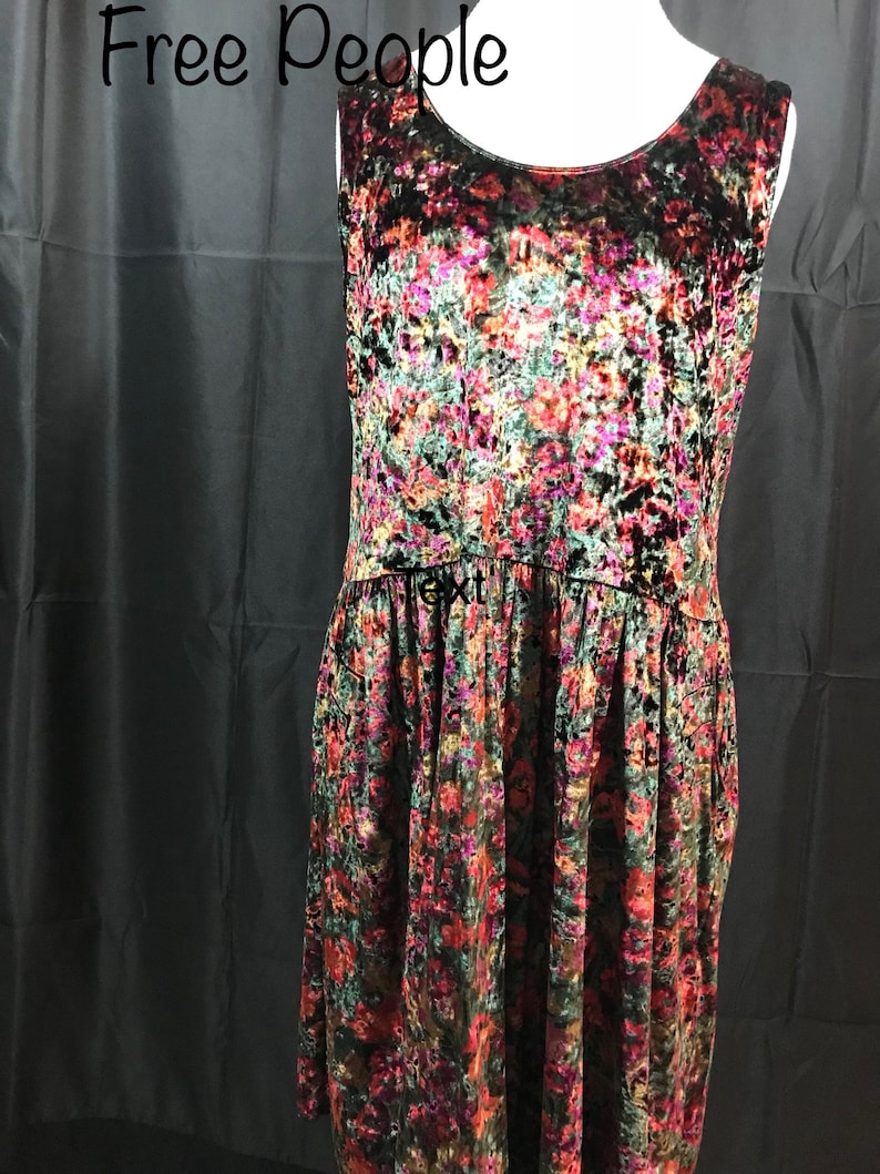 May include: A sleeveless, black velvet dress with a floral print in shades of red, pink, green, and gold. The dress has a scoop neck and a flowy skirt.