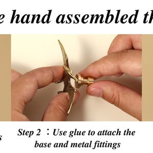 Op de afbeelding: Een drieluikafbeelding die de montage van een decoratieve knop met een vleermuisachtig ontwerp laat zien. De tekst luidt "How we hand assembled the knob". Stap 1 toont componenten, stap 2 de montage en stap 3 de afgewerkte knop.