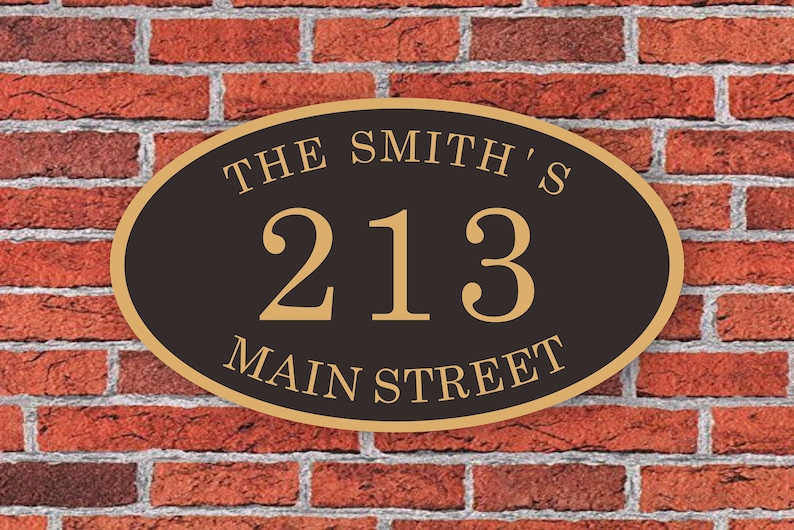 May include: Oval-shaped house number plaque with a black background and gold lettering. The plaque reads "The Smith's 213 Main Street".