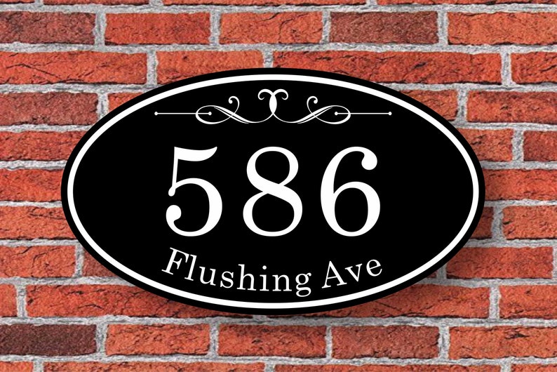 May include: Black oval-shaped house number sign with white lettering. The number 586 and the street name Flushing Ave are displayed on the sign.