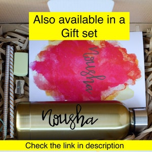May include: A gift set featuring a gold water bottle with the name "Nousha" on it. The set also includes a card with a watercolour design and the name "Nousha" written on it. The text "Also available in a Gift set" is at the top of the image.