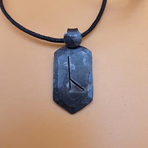 May include: A black leather cord necklace with a black metal pendant featuring a rune symbol.