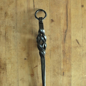 May include: A black metal fireplace poker with a twisted handle and a ring at the top.
