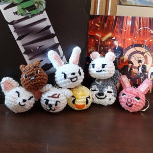 Può includere: Una collezione di otto portachiavi di animali all'uncinetto. I portachiavi sono realizzati in filato bianco, marrone, grigio, rosa e giallo. Gli animali includono un coniglio, un orso, un cane, un'anatra e un maiale.