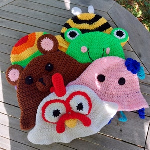 Può includere: Cinque cappelli all'uncinetto in vari colori e design di animali. I cappelli sono un'ape, una rana, un orso, un pollo e un maiale. I cappelli sono tutti fatti a mano e hanno dettagli unici.