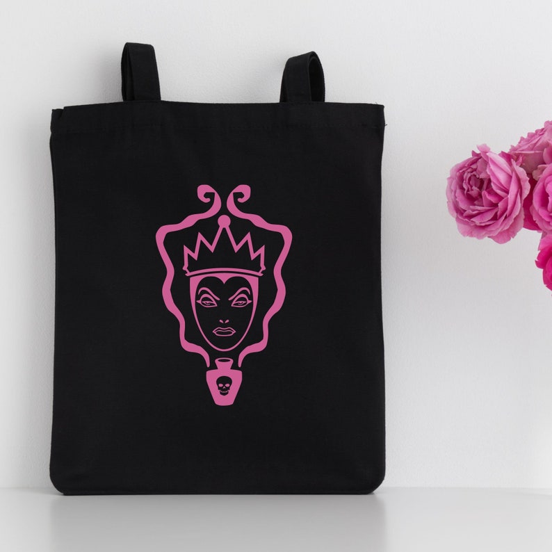 May include: Black tote bag with a pink silhouette of the Evil Queen from Snow White. The Evil Queen is wearing a crown and holding a poisoned apple.