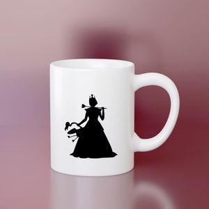 May include: White ceramic mug with a black silhouette of a queen wearing a crown and holding a scepter, riding a swan.