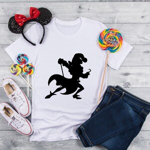 May include: White t-shirt with a black silhouette of Captain Hook from Peter Pan. The shirt is laid out on a wooden surface with a pair of white sneakers, blue jeans, and a red and black bow headband.