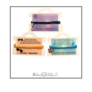 May include: Three friendship bracelets with themed charms and cards. One black bracelet with a musical note charm, one tan bracelet with sunglasses, and one blue bracelet with a soccer ball charm. Each card has song lyrics.