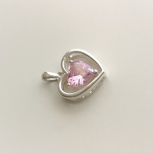 Peut inclure: Pendentif en argent en forme de c&oelig;ur avec une pierre pr&eacute;cieuse rose. Le pendentif pr&eacute;sente un design d&eacute;licat et ouvert, mettant en valeur la pierre pr&eacute;cieuse en forme de c&oelig;ur. La pierre est rose clair, ajoutant une touche d'&eacute;l&eacute;gance.