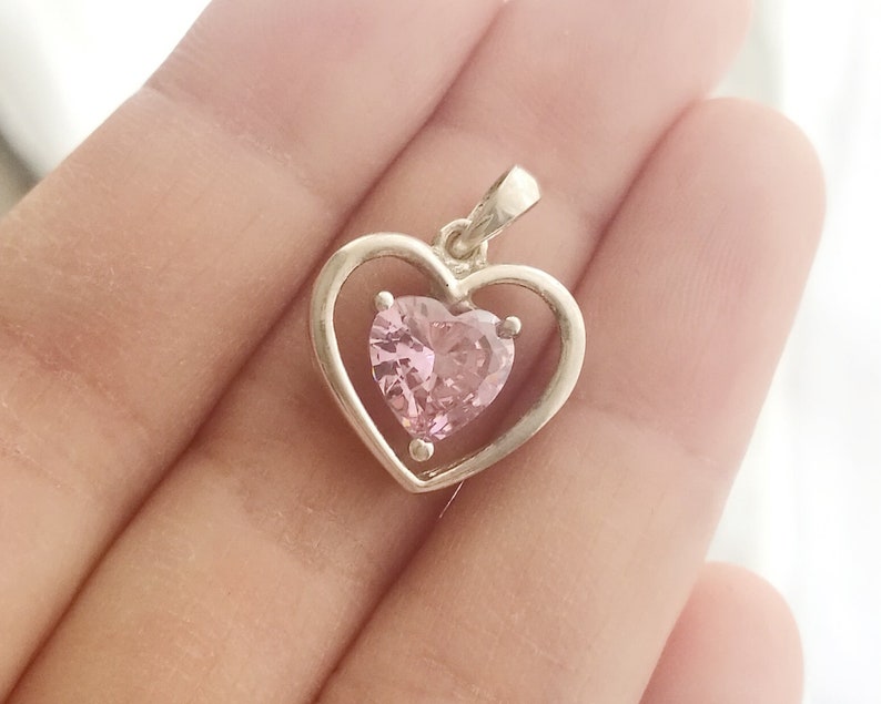 Peut inclure: Un pendentif en argent avec un motif en forme de c&oelig;ur. Le pendentif a un cadre ext&eacute;rieur en forme de c&oelig;ur et une pierre pr&eacute;cieuse rose en forme de c&oelig;ur &agrave; l'int&eacute;rieur. Le pendentif est con&ccedil;u pour &ecirc;tre port&eacute; en collier.