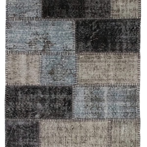 May include: A patchwork rug with a variety of shades of gray and brown. The rug is made of different pieces of fabric that have been sewn together.
