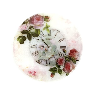 May include: Round decorative clock featuring a vintage design with a clock face and Roman numerals. The clock face is surrounded by pink roses and green leaves. The word "WINNER" is printed on the clock face.